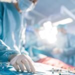 Close-up Shot in the Operating Room of Surgical Table with Instruments, Assistant Picks up Instruments for Surgeons During Operation. Surgery in Progress. Doctors Performing Surgery.